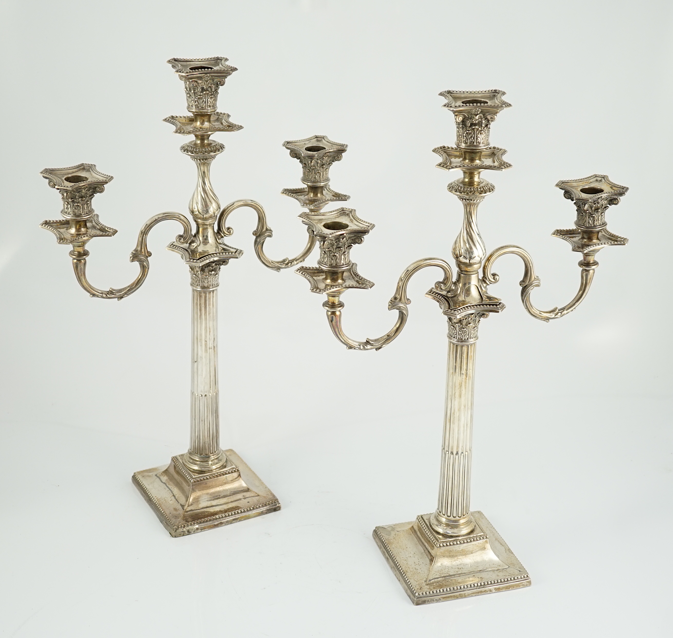 A matched pair of late 19th/early 20th century silver two branch, three light candelabrum